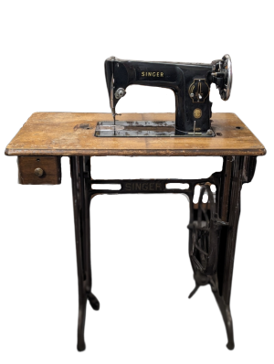 A vinateg singer sewing machine table. A black sewing machine on a wooden table with cast iron base.