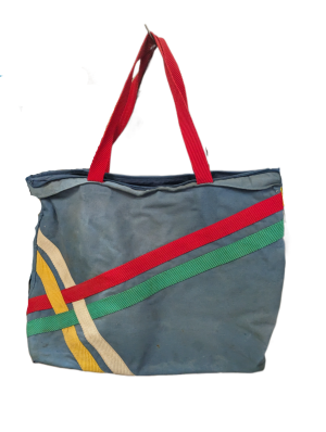 A 1980's style tote bag in blue denim. There are multicoloured stripes on the side and a red fabric handle