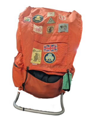 Retro orange expedition style rucksack with metal frame. Pack features various destination patches.